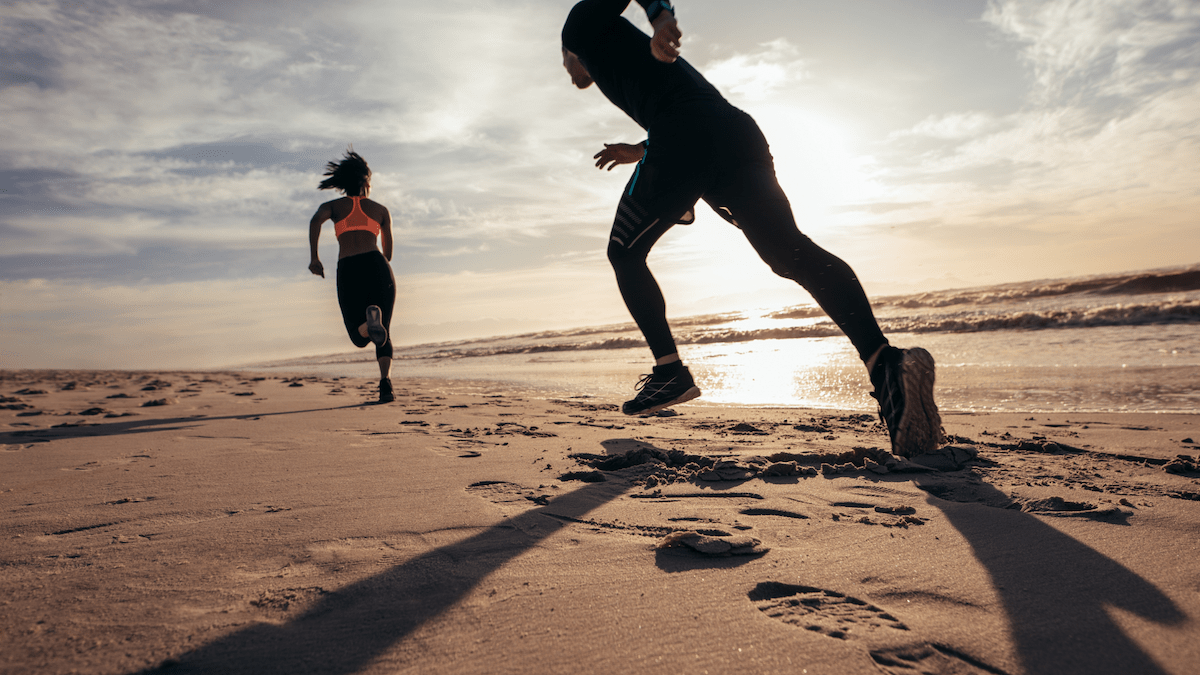 man and woman running on beach